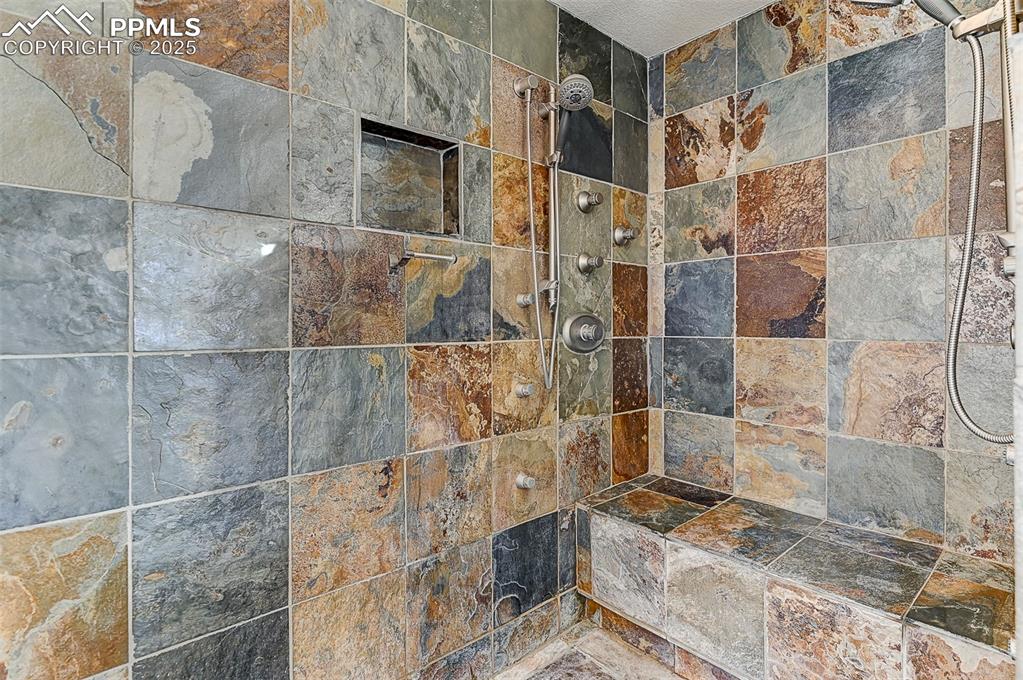 Image 35 of 42: Walk-in shower with dual-body spray jets, sitting area and