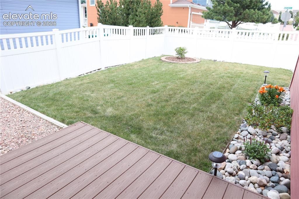 Image 27 of 34: Fully Fenced Backyard with Deck and Landscaping.