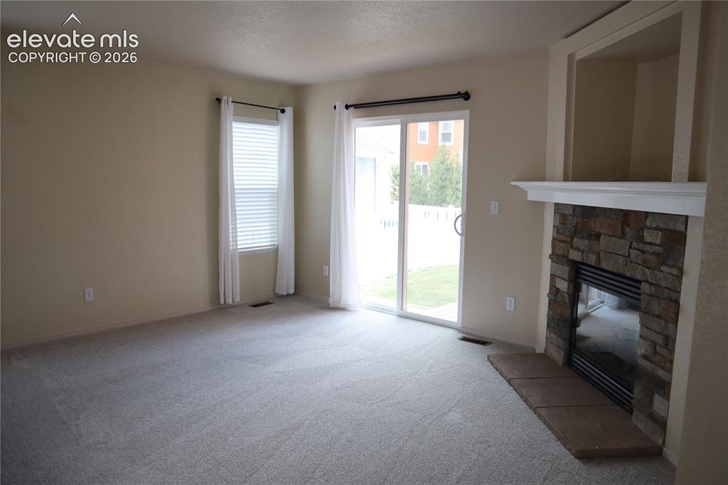 Image 4 of 34: Living Room looking to the Fireplace and Sliding Doors.