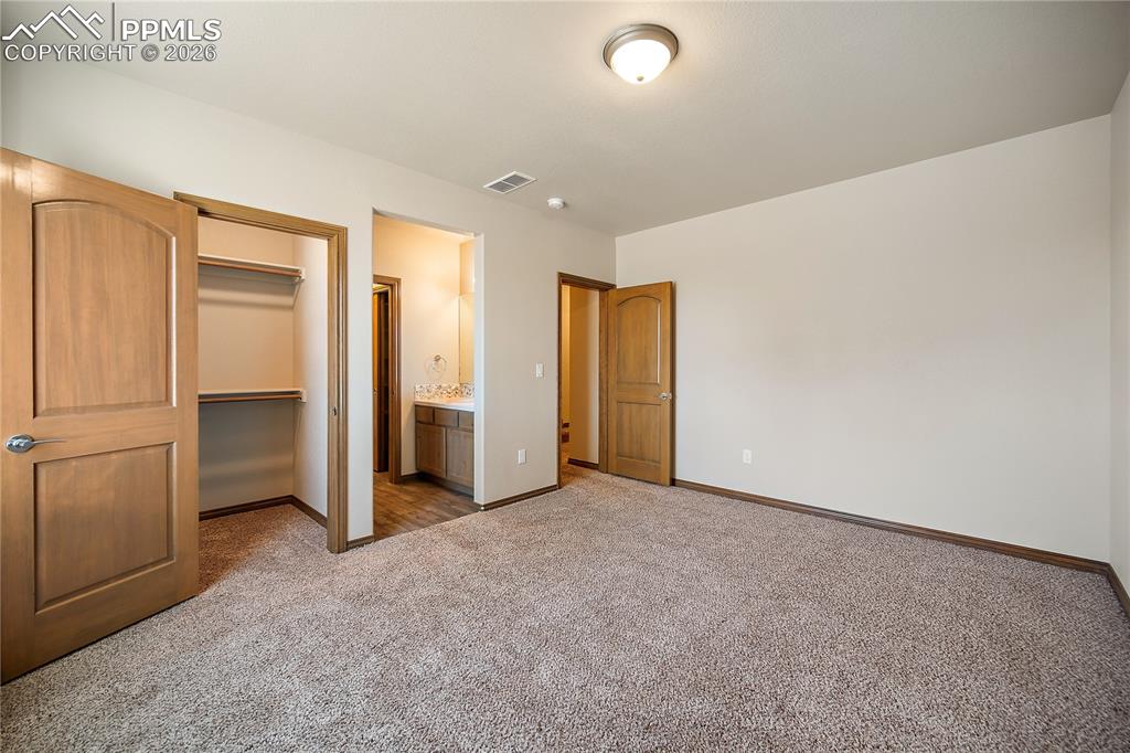 Image 29 of 49: Basement bedroom with carpet, walk in closet and attached Jack-n- Jill bath
