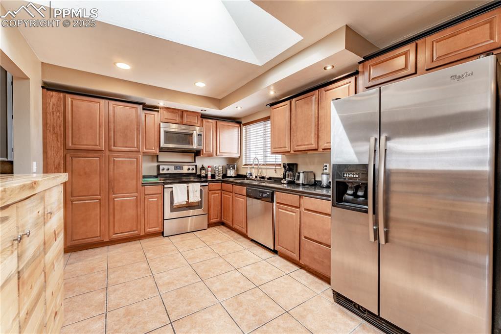 Image 10 of 39: Kitchen featuring stainless steel appliances, light tile patterned floors, 