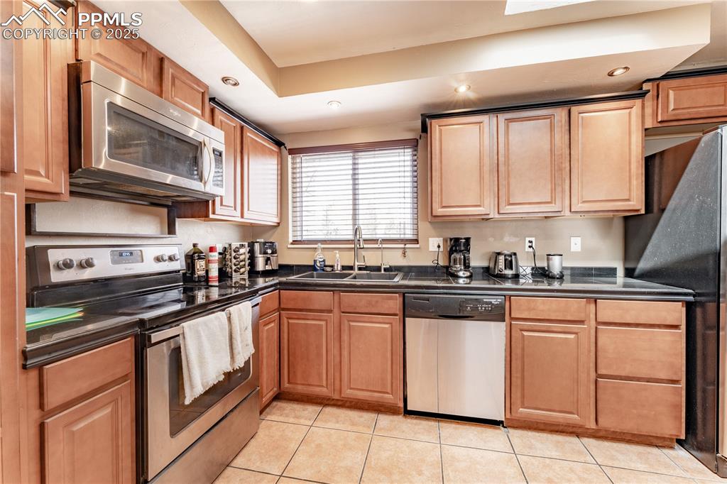 Image 11 of 39: Kitchen with stainless steel appliances, light tile patterned floors, and r
