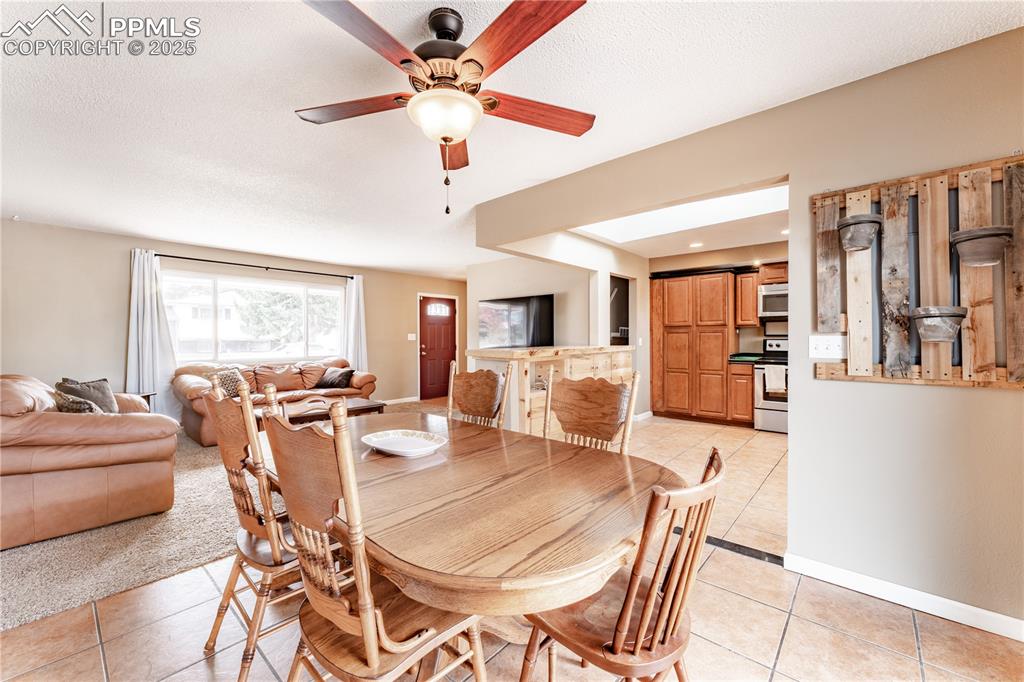 Image 12 of 39: Dining space featuring light tile patterned flooring, a ceiling fan, and a 