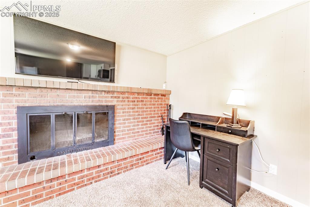 Image 28 of 39: Carpeted office space with a fireplace and a textured ceiling