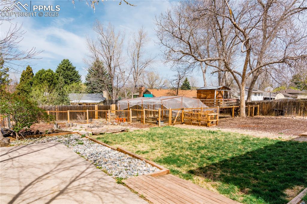 Image 4 of 39: Fenced backyard with an outdoor structure and a vegetable garden