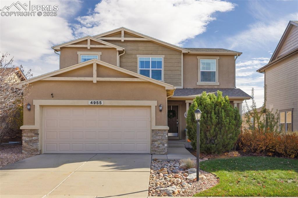 Caption: Craftsman house featuring stone siding, driveway, stucco siding, and a shingled roof