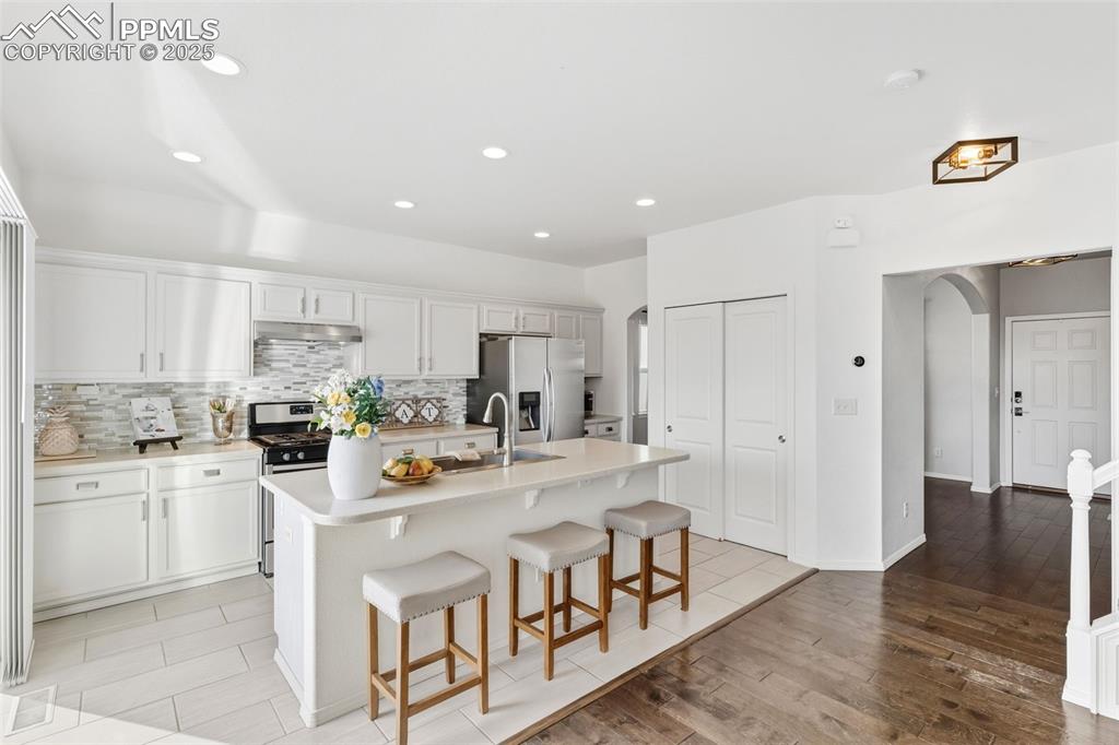 Image 13 of 41: Kitchen featuring arched walkways, a kitchen breakfast bar, decorative back