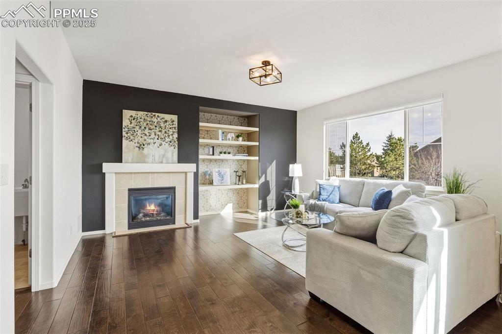 Image 17 of 41: Living room featuring dark wood-style floors, built in shelves, and a tiled