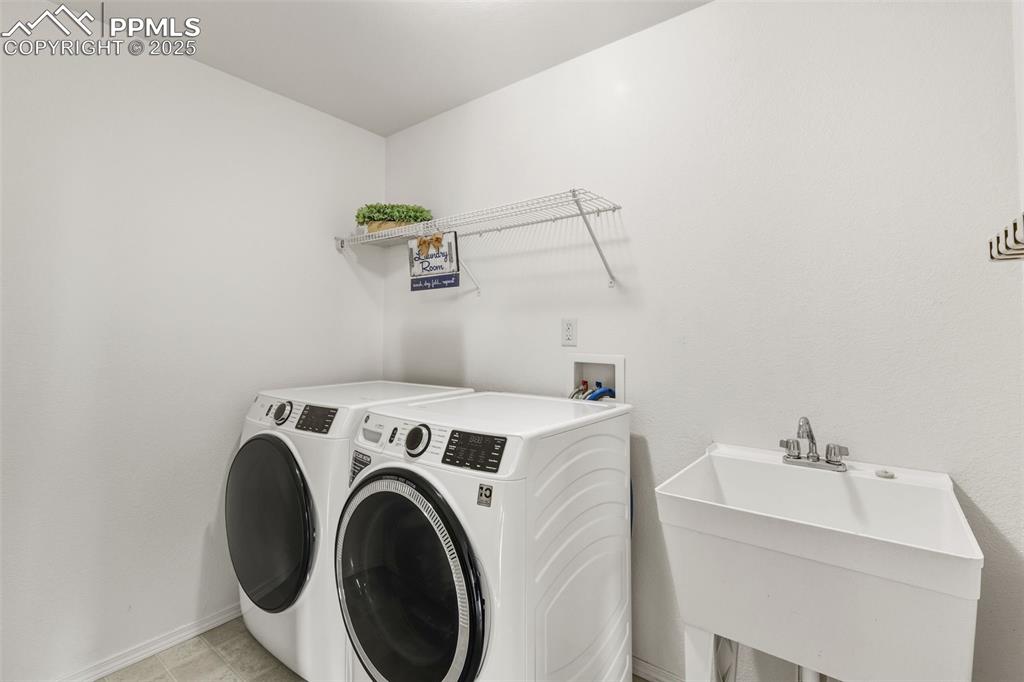 Image 20 of 41: Laundry area with independent washer and dryer and light tile patterned flo