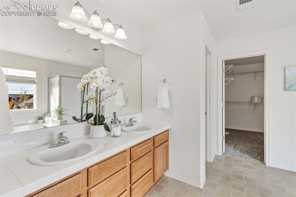 Image 23 of 41: Full bath featuring double vanity, a spacious closet, and a stall shower