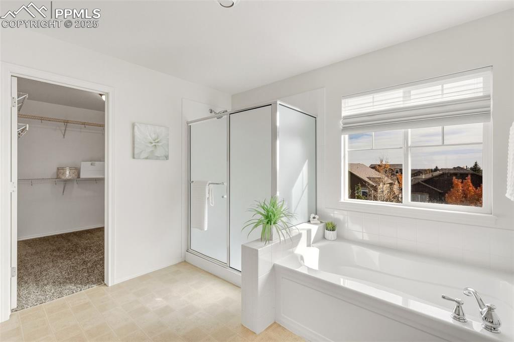 Image 24 of 41: Bathroom with a garden tub, a stall shower, a spacious closet, and light fl