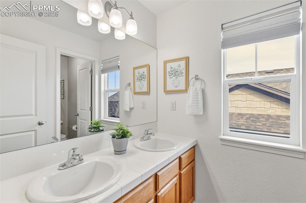 Image 28 of 41: Bathroom featuring double vanity and a chandelier