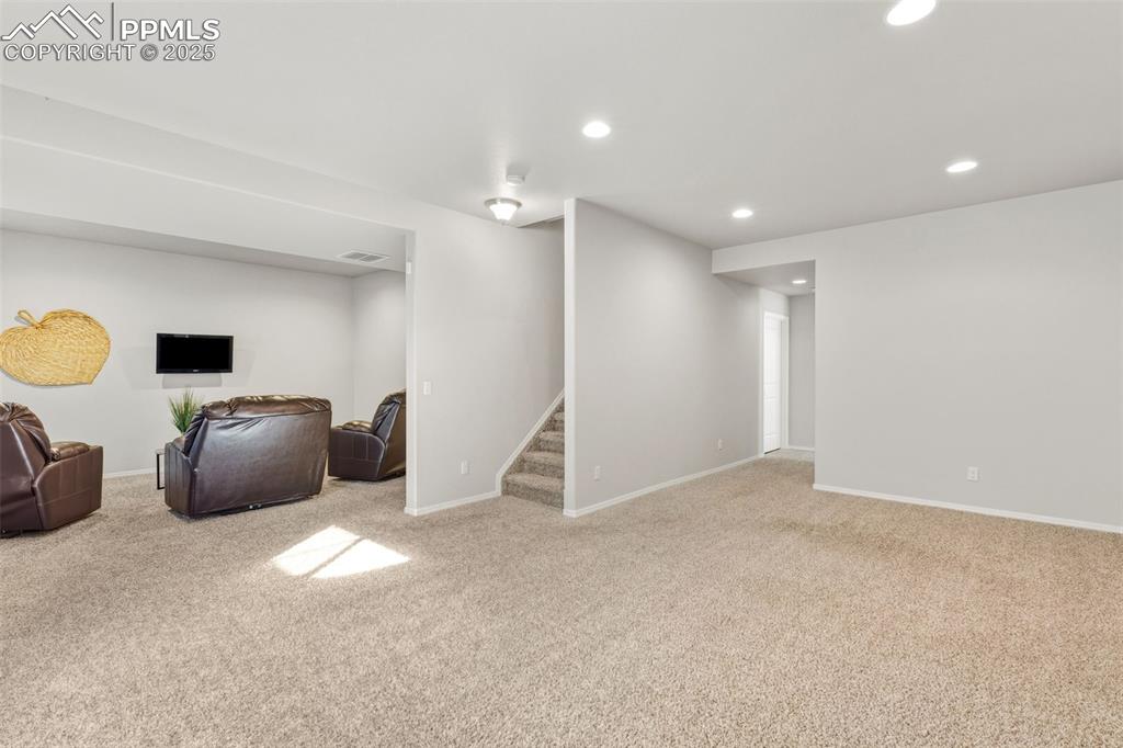 Image 30 of 41: Finished below grade area with recessed lighting, light carpet, and stairwa
