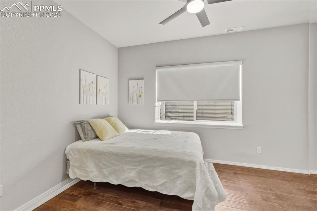 Image 33 of 41: Bedroom with wood finished floors and a ceiling fan