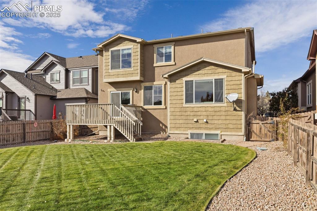 Image 37 of 41: Back of house featuring a fenced backyard, a deck, and stucco siding