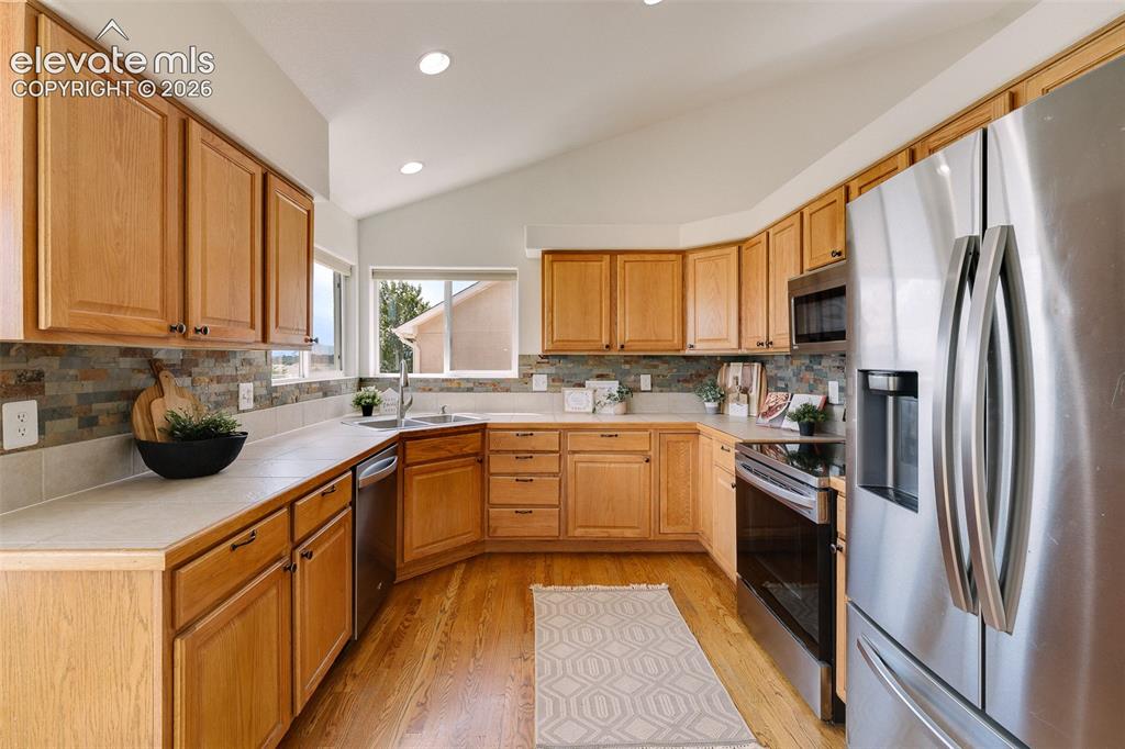 Image 11 of 47: Kitchen featuring wood-finish cabinetry, stainless steel appliances, a tile