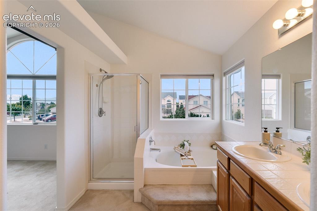 Image 23 of 47: Vaulted ceiling, glass-enclosed shower, soaking tub with tiled surround, wo