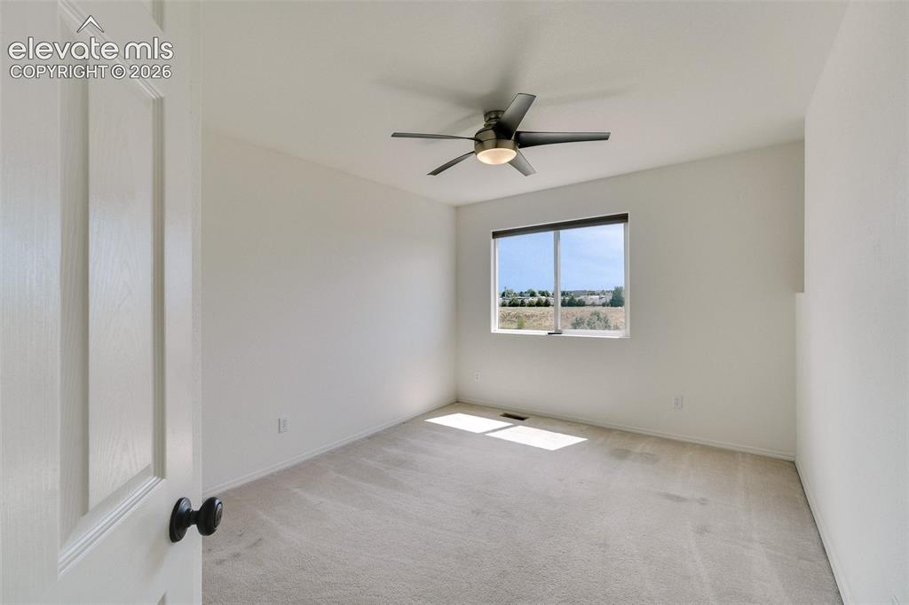 Image 25 of 47: Carpeted flooring, a window with a roller shade, and a ceiling fan with int