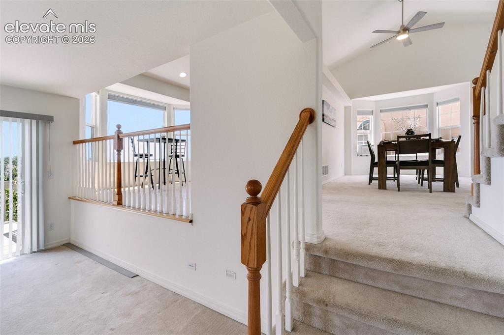 Image 34 of 47: Staircase with wood newel posts and balusters, vaulted ceilings, and bay wi