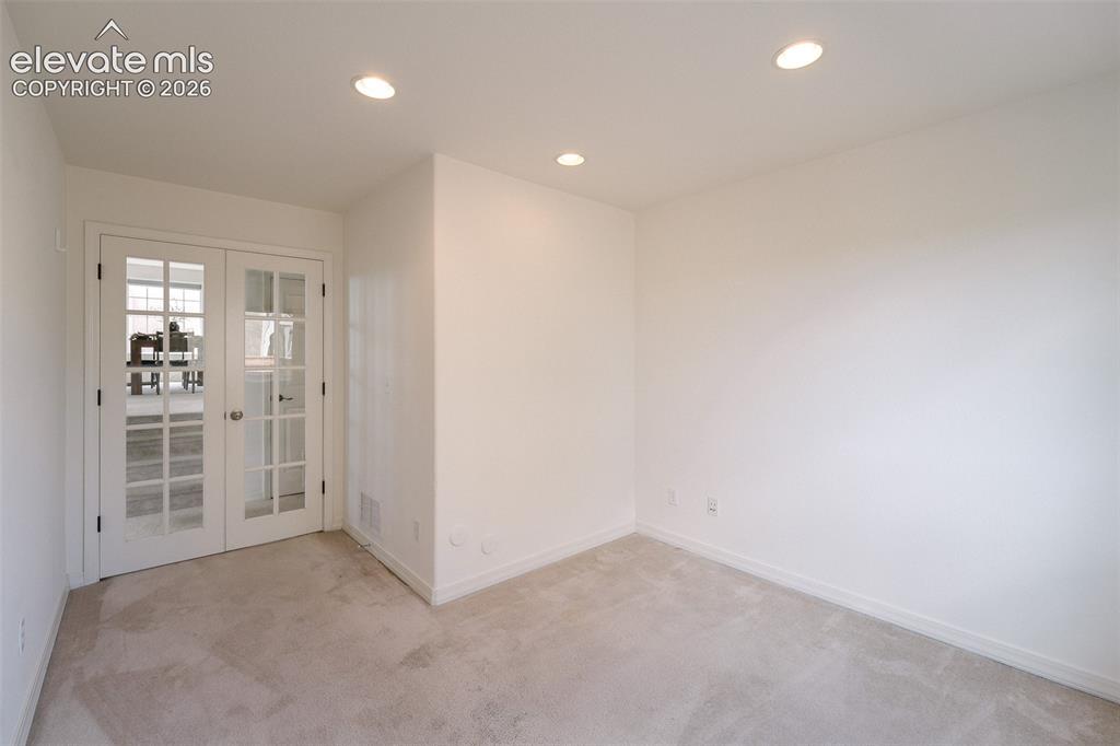 Image 37 of 47: White French doors with clear glass panes, recessed ceiling lighting, light