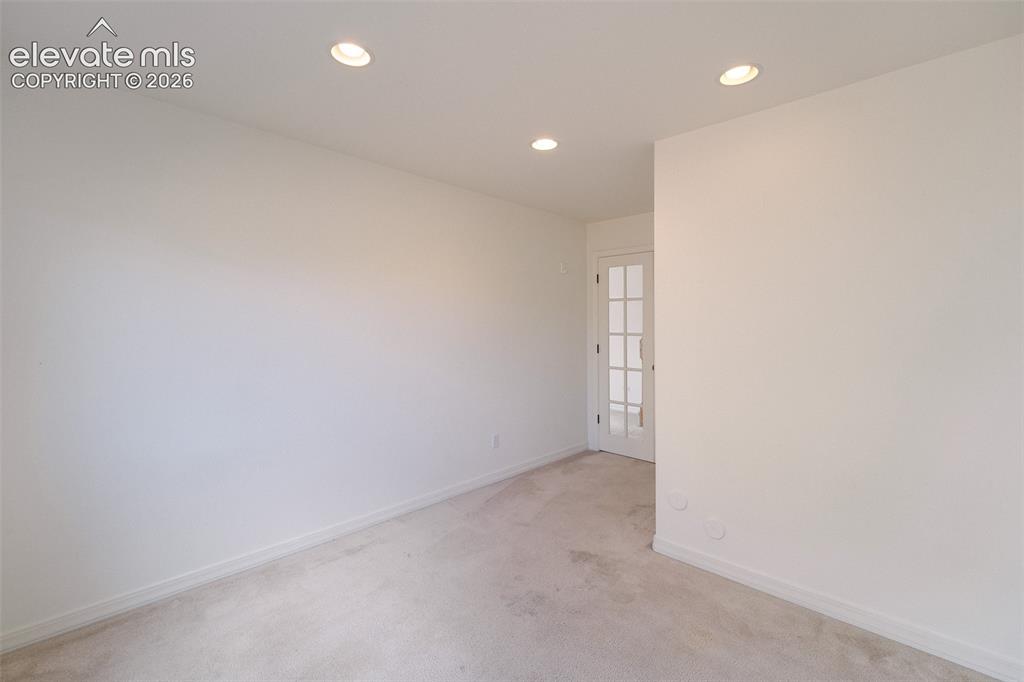 Image 38 of 47: Recessed lighting, light-toned carpeting, and a french door with multi-pane