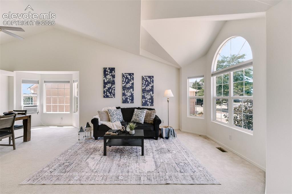 Image 4 of 47: Vaulted ceilings, arched window, bay window, light-toned carpeting, and a c