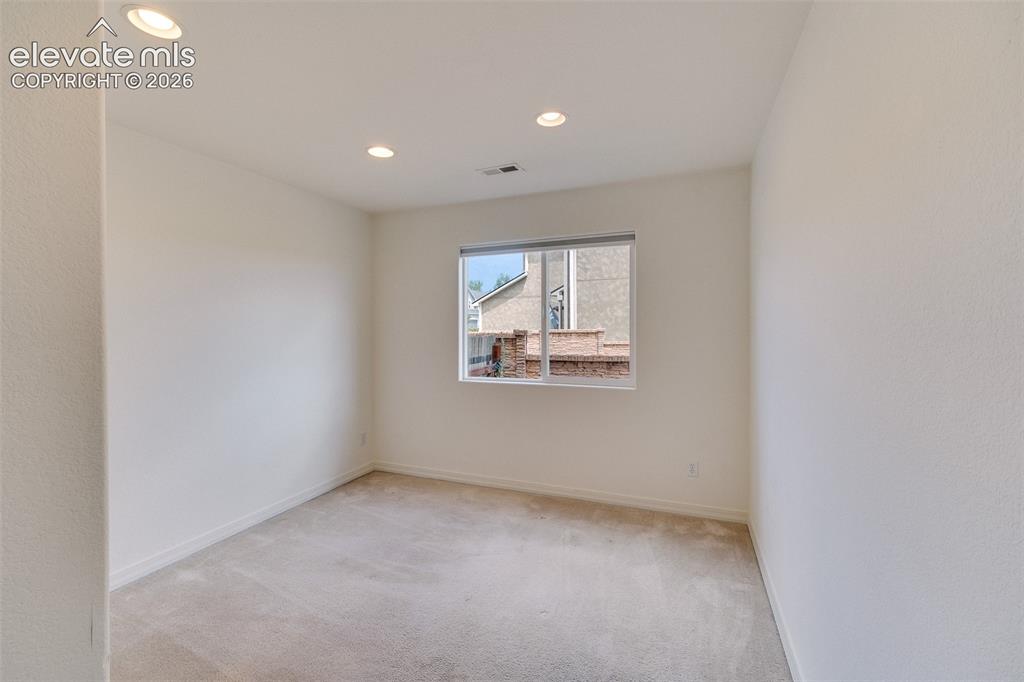 Image 40 of 47: Recessed ceiling lighting illuminates a room with light-toned carpet floori