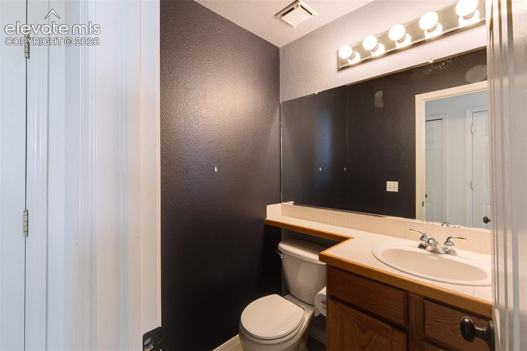 Image 41 of 47: Bathroom vanity with a built-in sink, wood-finish cabinetry, and a full-wid