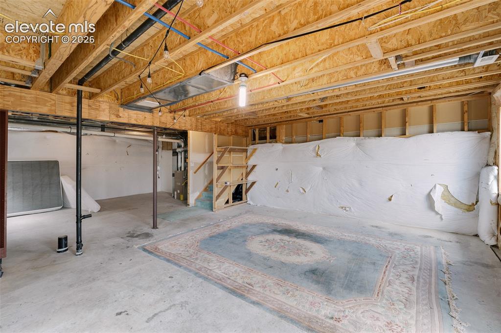 Image 43 of 47: Unfinished basement with exposed wood joists, concrete flooring, and visibl