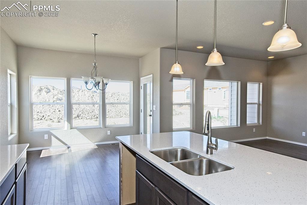 Image 12 of 25: Kitchen featuring dark wood-type flooring, a textured ceiling, light stone