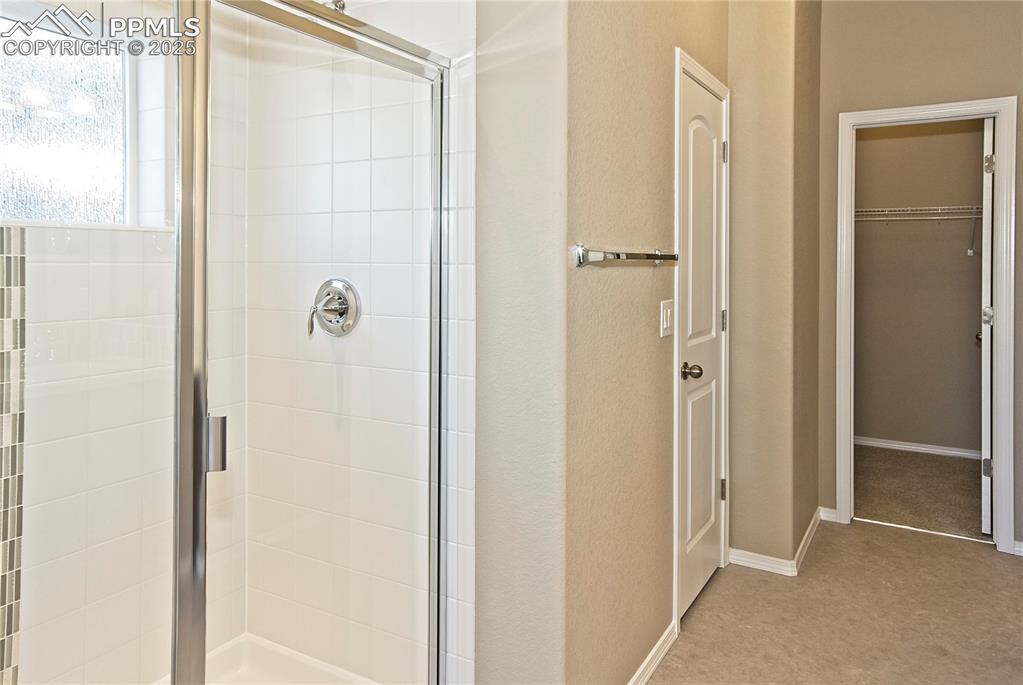 Image 16 of 25: Bathroom featuring a stall shower and a walk in closet
