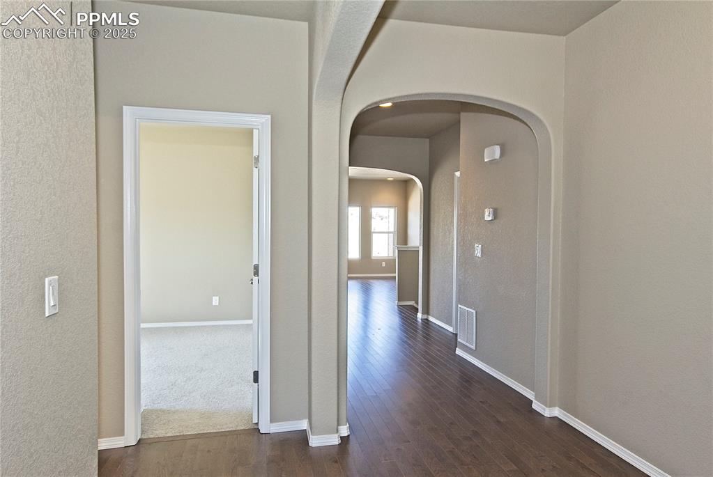 Image 4 of 25: Hallway with arched walkways and dark wood-type flooring
