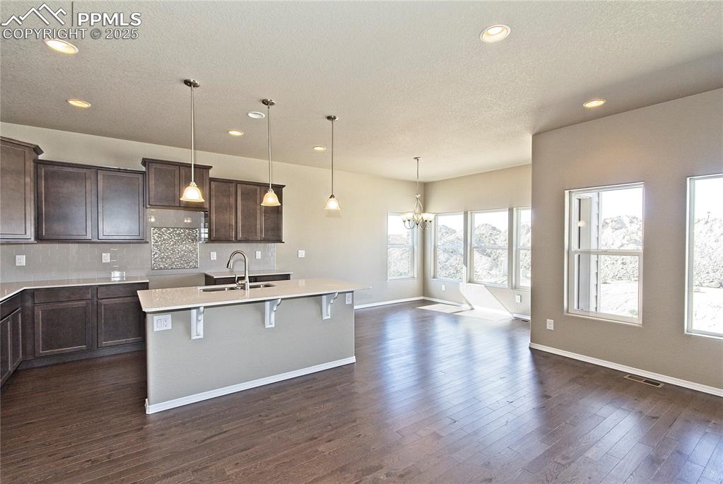 Image 8 of 25: Kitchen with a center island with sink, dark brown cabinets, a chandelier,