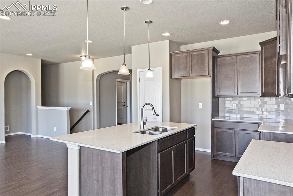 Image 9 of 25: Kitchen featuring a textured ceiling, dark wood-type flooring, backsplash,