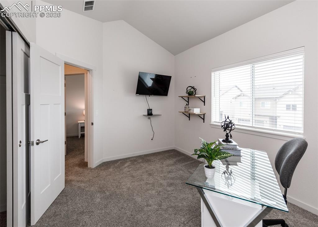 Image 36 of 46: Office with carpet floors and vaulted ceiling