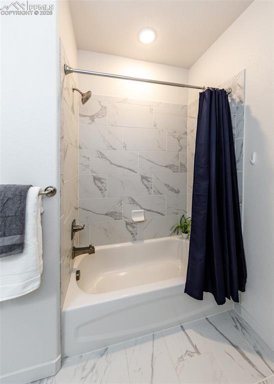 Image 38 of 46: Full bath featuring shower / bath combo with shower curtain and light marbl