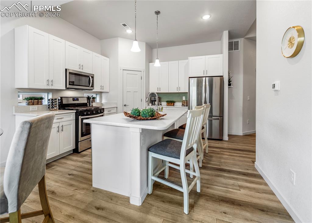 Image 9 of 46: Kitchen featuring stainless steel appliances, a kitchen bar, a kitchen isla