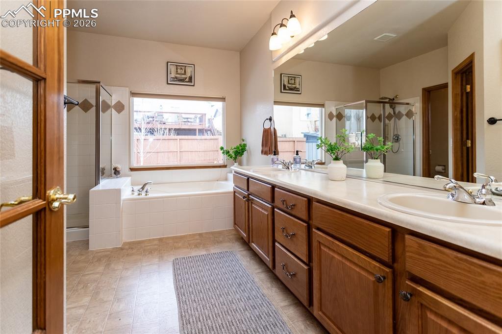 Image 24 of 50: Adjoining primary bathroom is separated with a glass door.