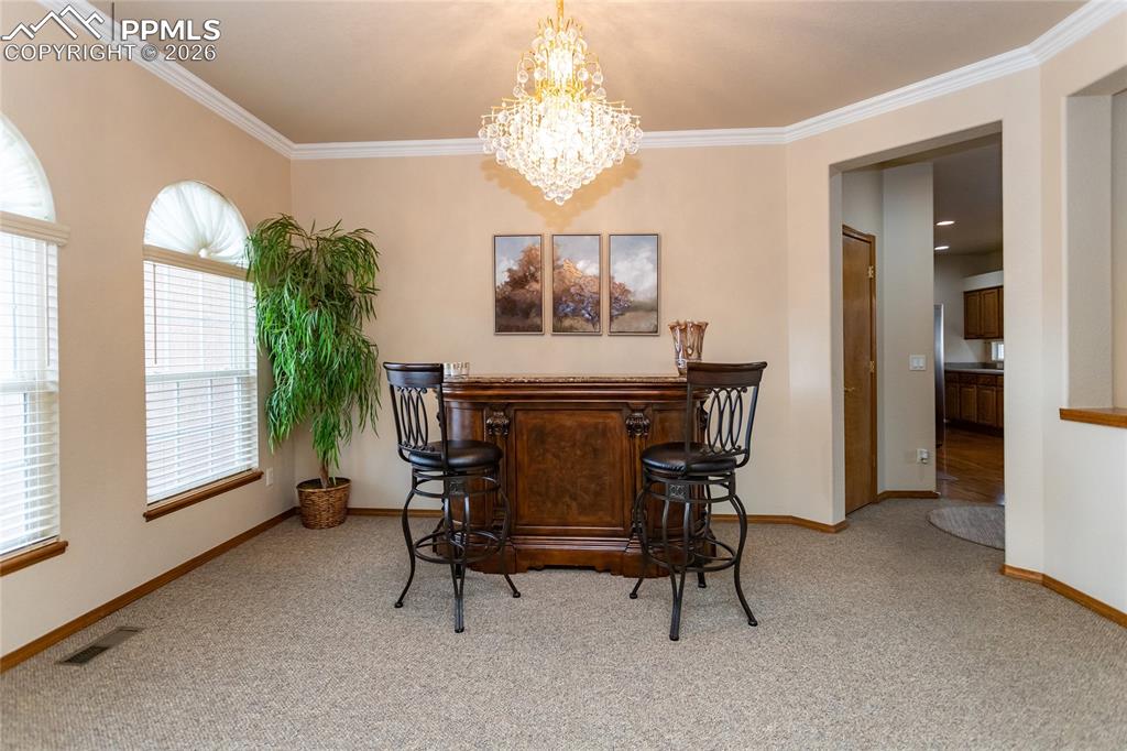 Image 9 of 50: Spacious dining room with crown molding and beautiful crystal chandelier.