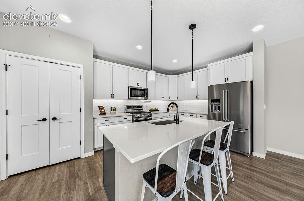 Image 14 of 47: Modern kitchen featuring a central island with a solid surface countertop,