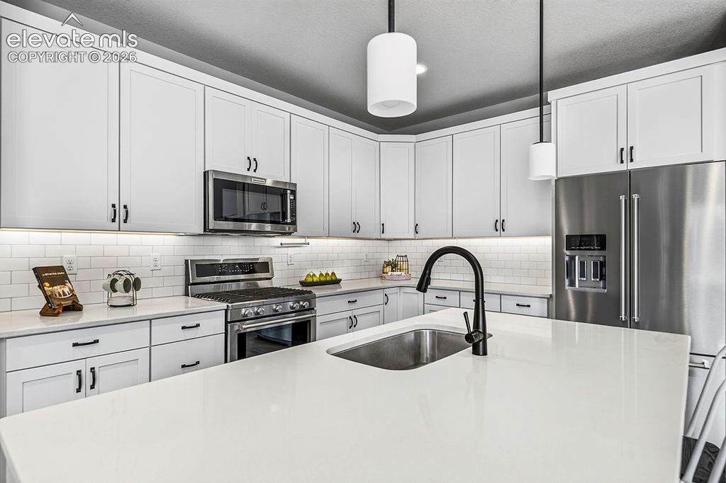 Image 15 of 47: Modern kitchen featuring a large island with an undermount sink and matte b