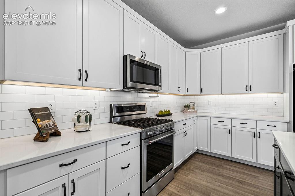 Image 18 of 47: Contemporary kitchen featuring white cabinetry with matte black hardware, s