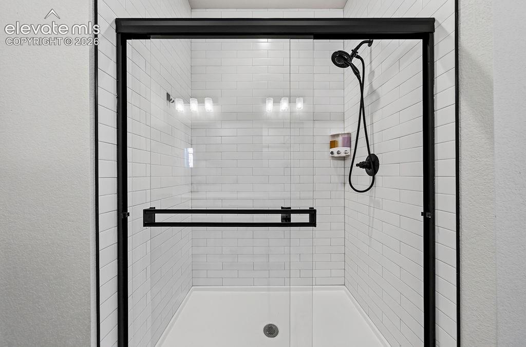 Image 29 of 47: Walk-in shower featuring a sliding glass door with matte black framing, whi