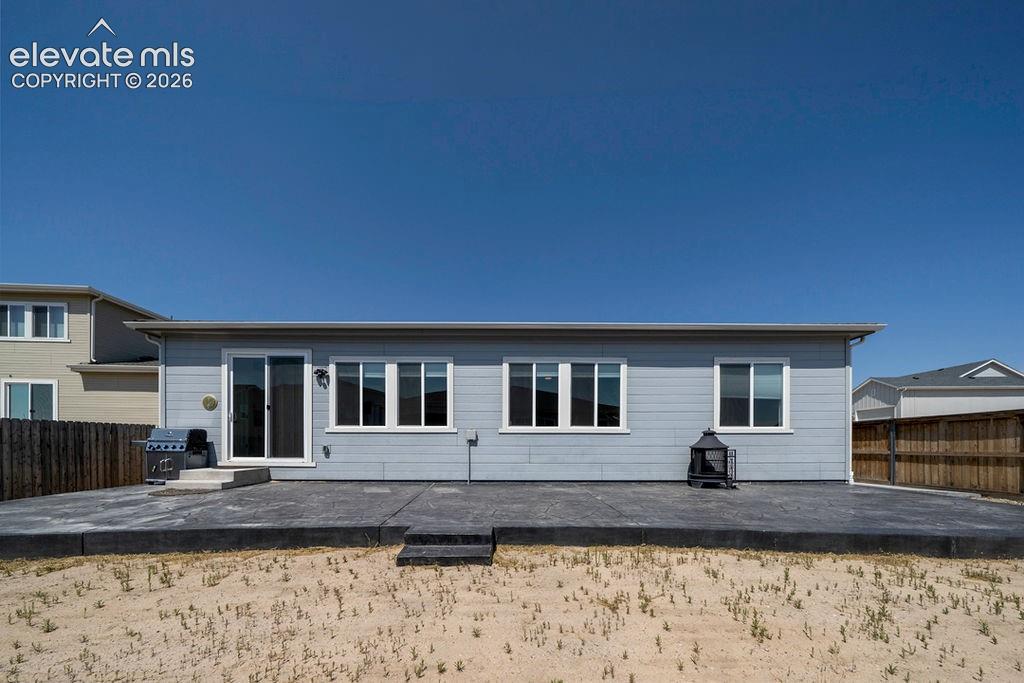 Image 4 of 47: Rear exterior featuring light blue siding, multiple windows, and a sliding
