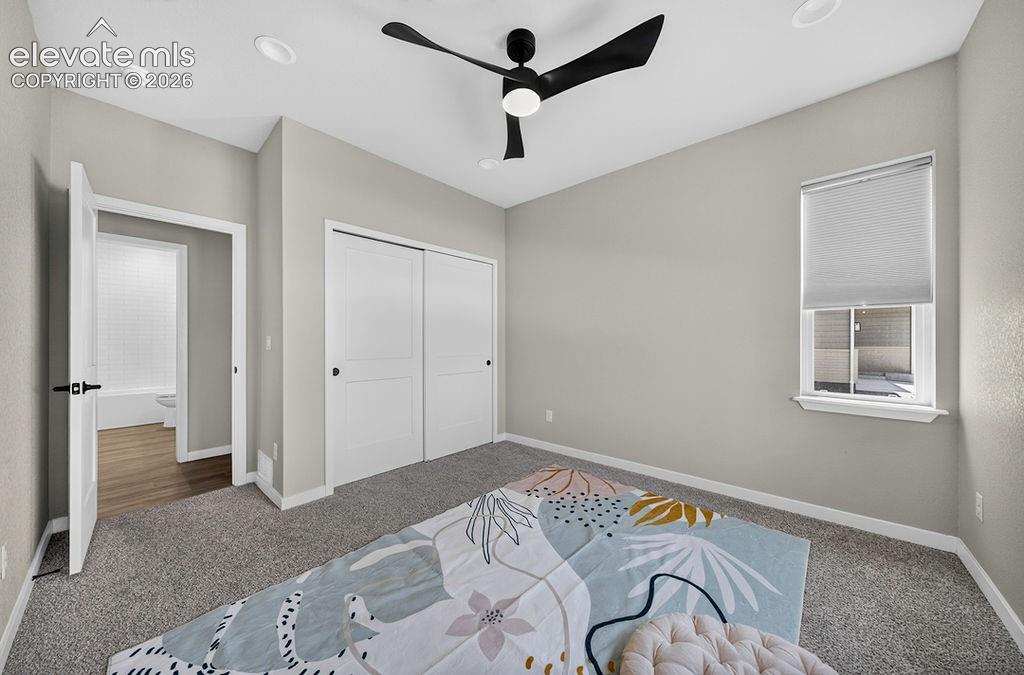 Image 40 of 47: Carpeted room with light grey walls, featuring a modern black ceiling fan w
