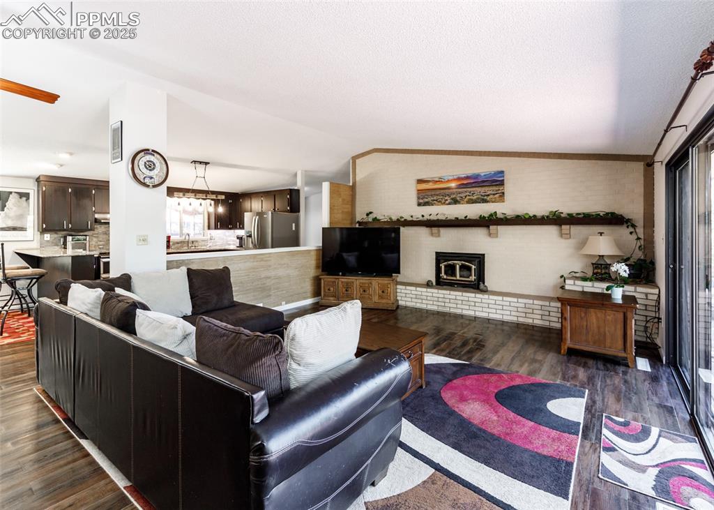 Image 2 of 33: Living room with dark wood finished floors, a wood stove, lofted ceiling, a