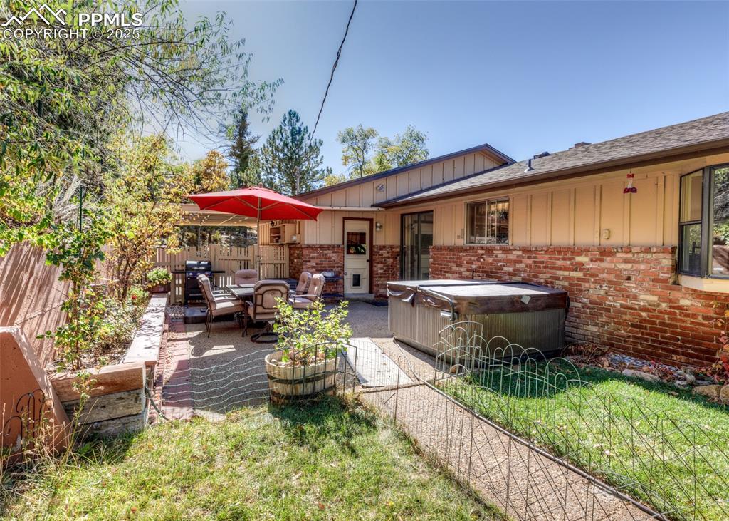 Image 22 of 33: Rear view of house featuring a hot tub, brick siding, a patio area, and boa