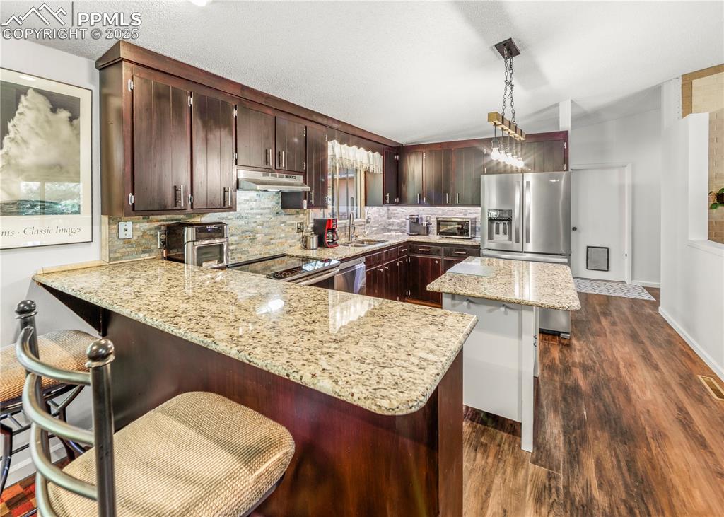 Image 7 of 33: Kitchen with a kitchen bar, a kitchen island, tasteful backsplash, light st