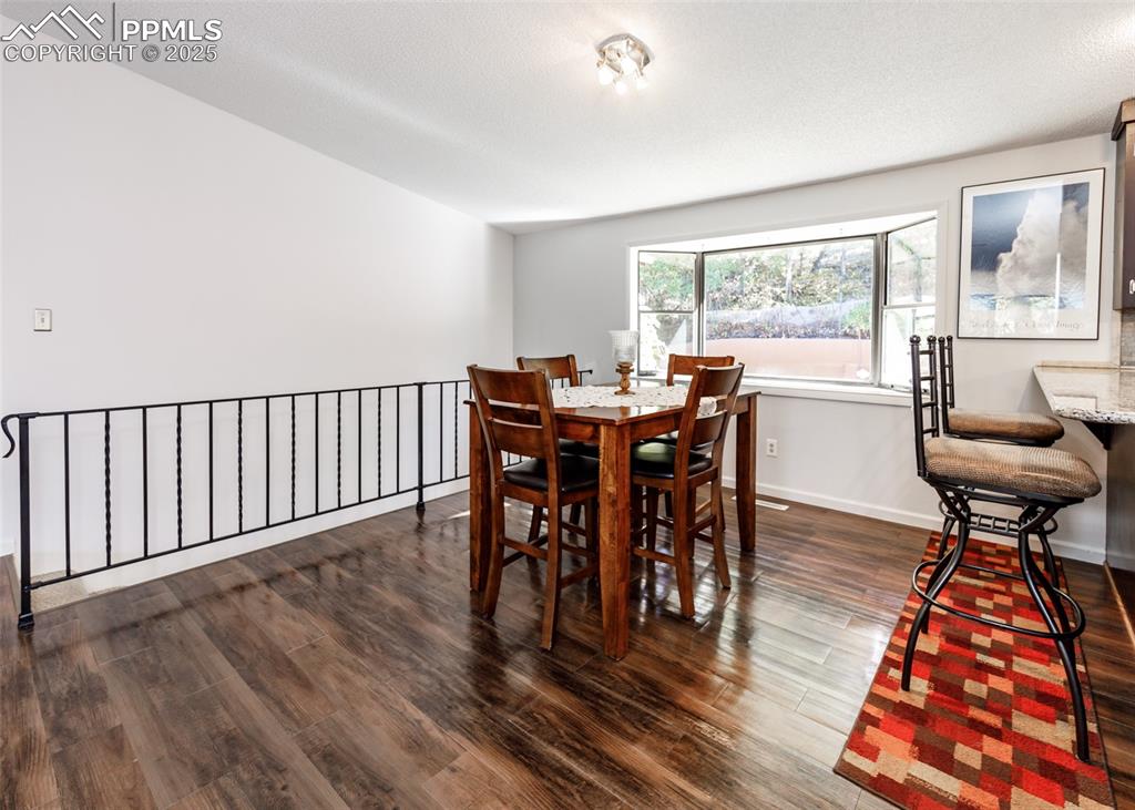 Image 8 of 33: Dining area featuring dark wood-style floors and baseboards