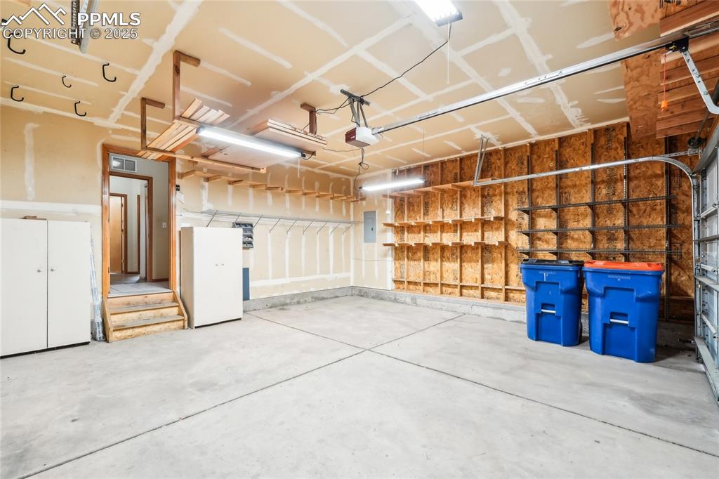 Image 35 of 49: Garage with electric panel and a garage door opener